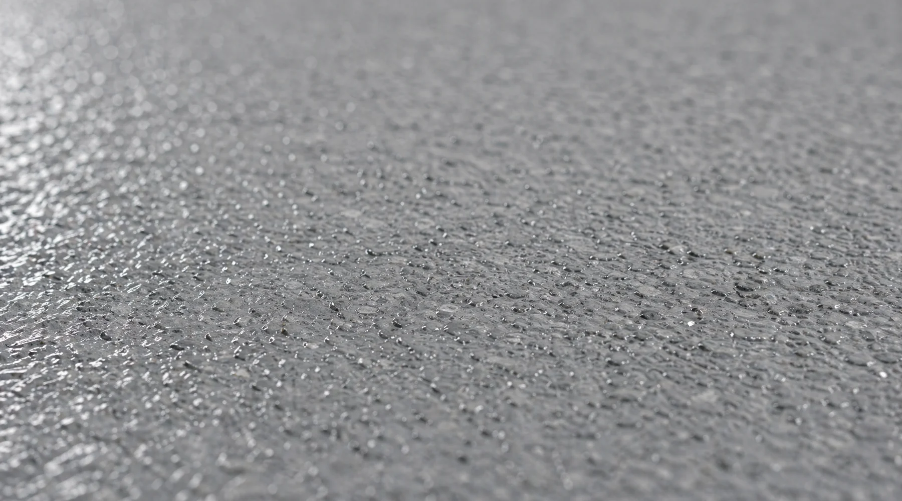 Close-up macro of anti-slip floor surface showing aggregate texture oblique light highlighting the surface