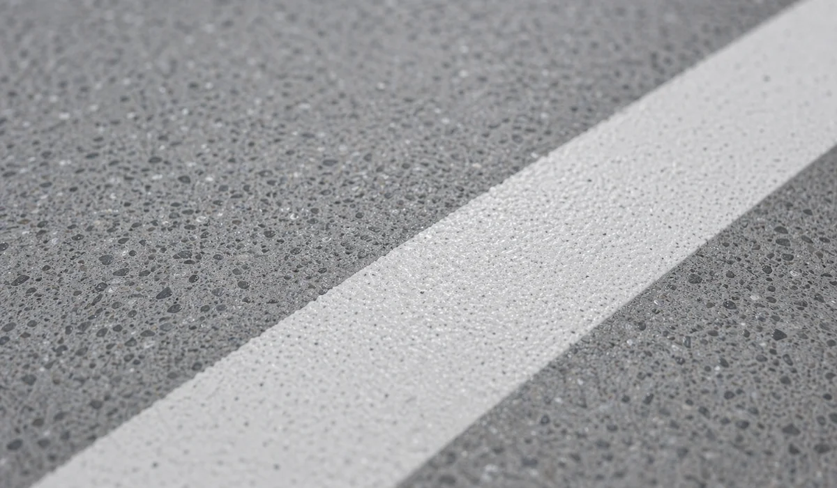 Close-up of crisp white line on deck coating with aggregate showing thermoplastic paint visible