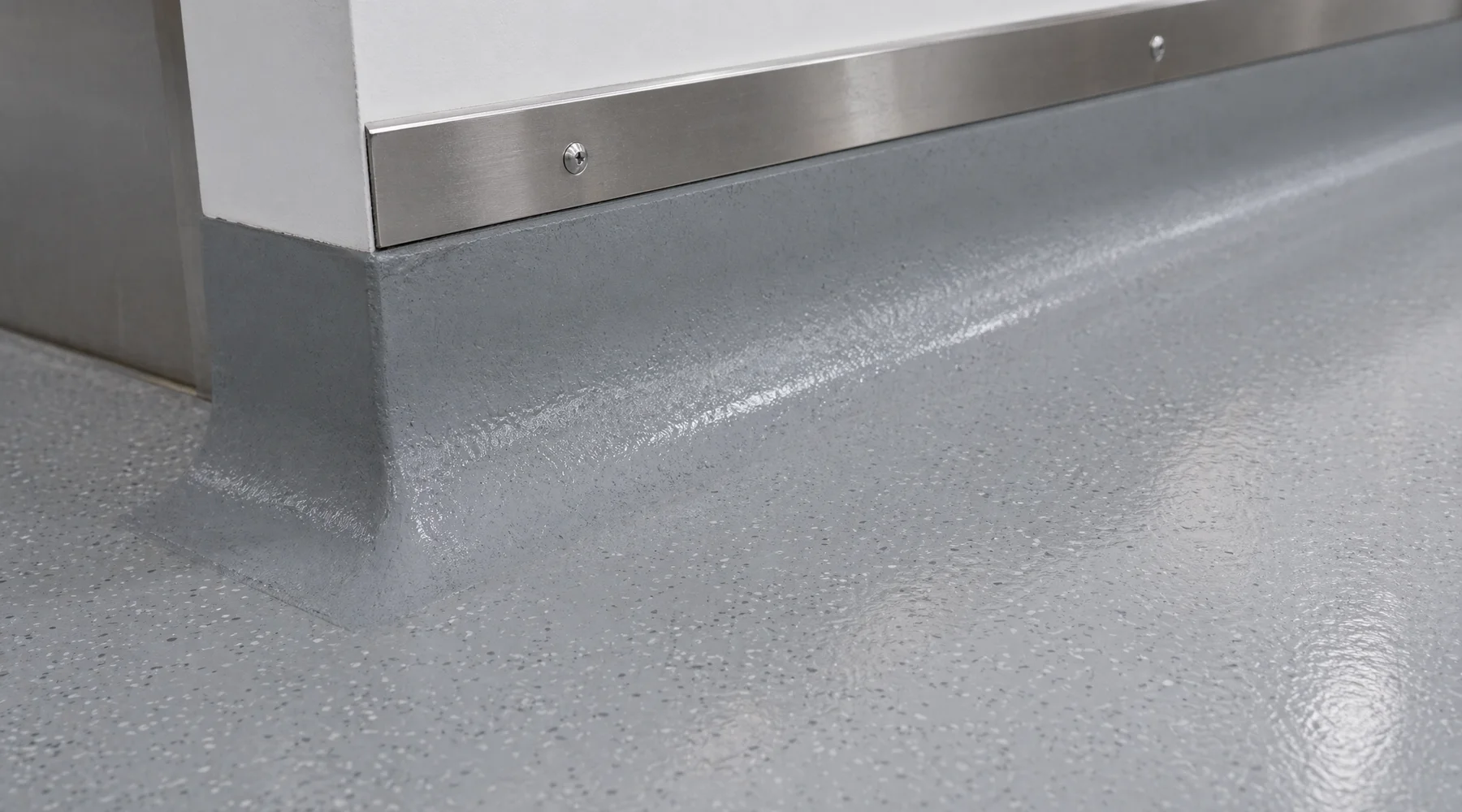 Close-up of integral hygienic PU cove at floor-wall junction smooth radius no cracks stainless